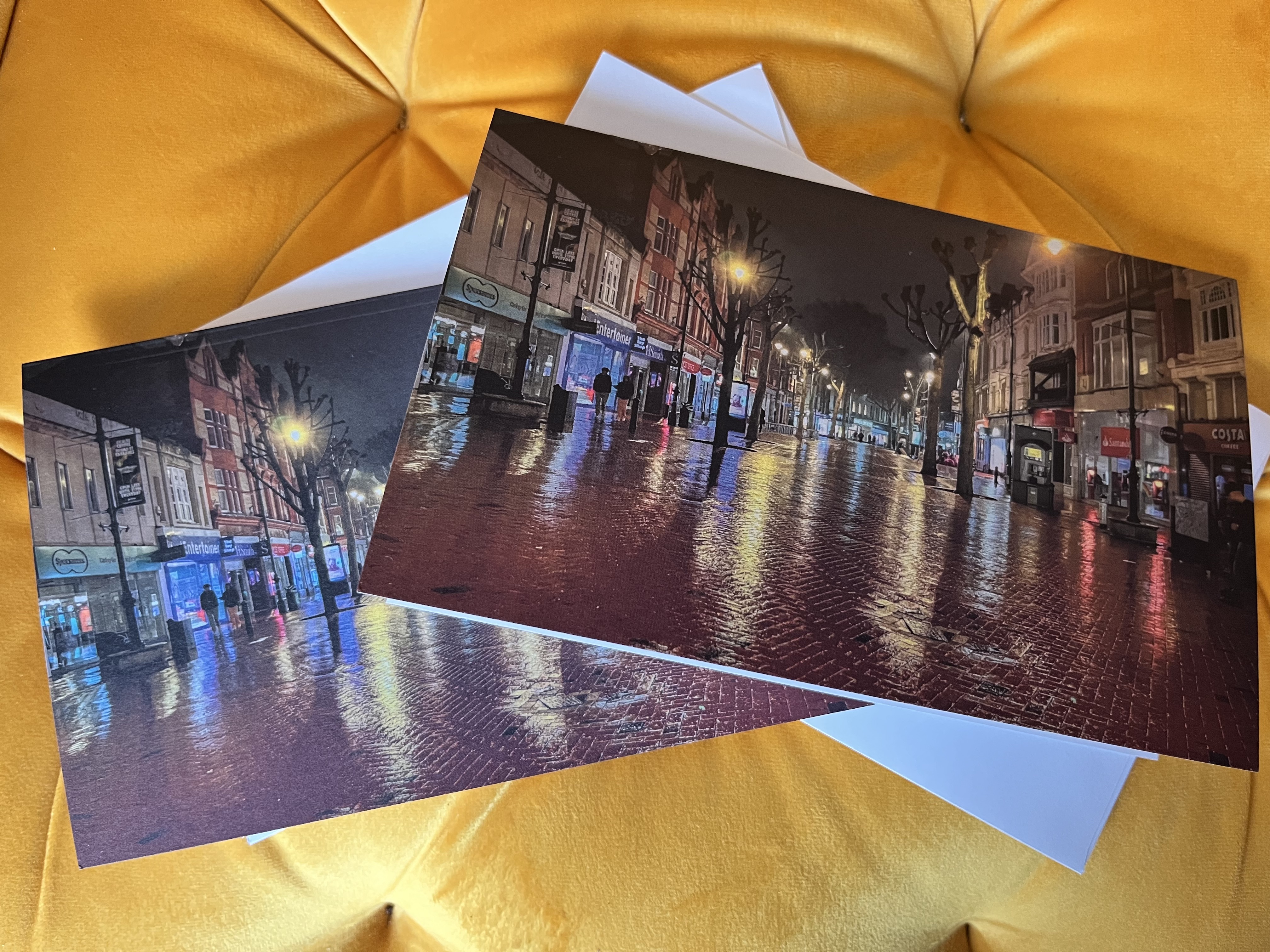 A photograph of Broad Street in Reading, taken at night after it had rained. The shop and street lights are reflected on the wet ground.